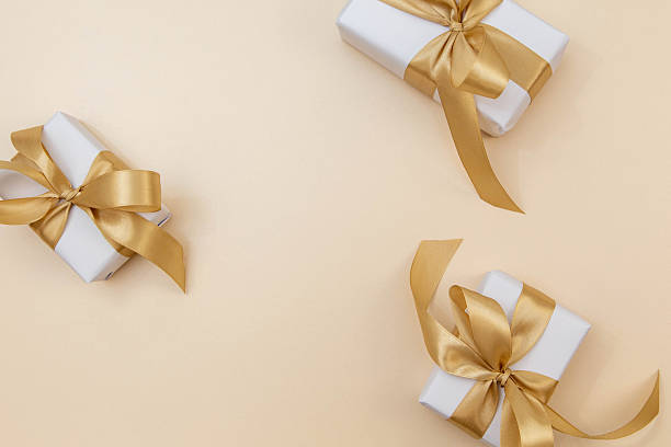 istock Gift boxes with golden satin ribbons on soft beige background. Elegant minimal composition with copy space for text or logo. 2243362120
