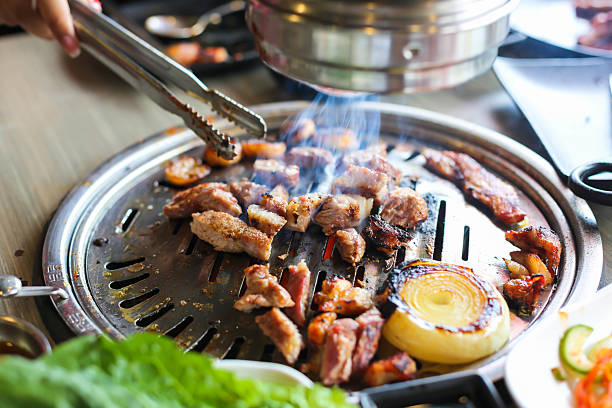 istock Korea BBQ style restaurant. Asian traditional pickle vegetable ingredients on table with people grilling background. 2243364538