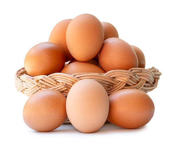 Many brown chicken eggs in stack in wicker basket are isolated on white background with clipping path.