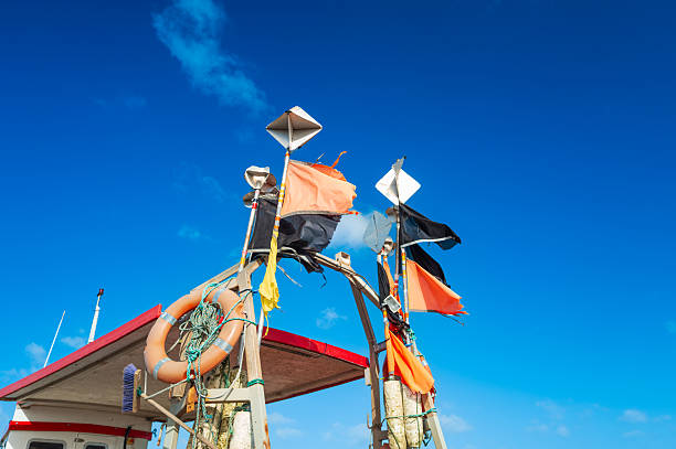 Abstract view of navigation flags seen in the wind against a clear blue sky. The flags belong to a small commercial fishing trawler located on the North Sea coast.