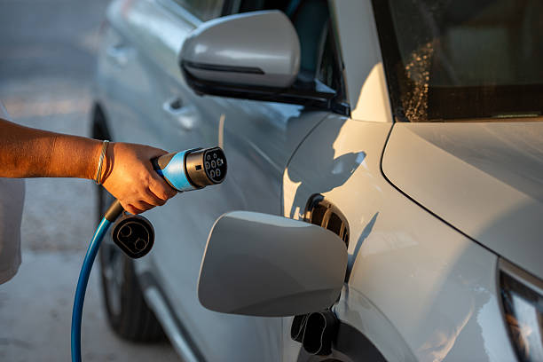 istock Person Charging Electric Car with Blue Power Cable. 2243377062