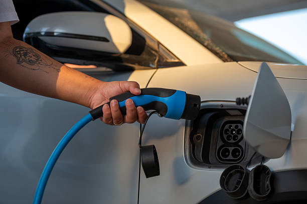 Person Charging Electric Vehicle with Blue Cable.