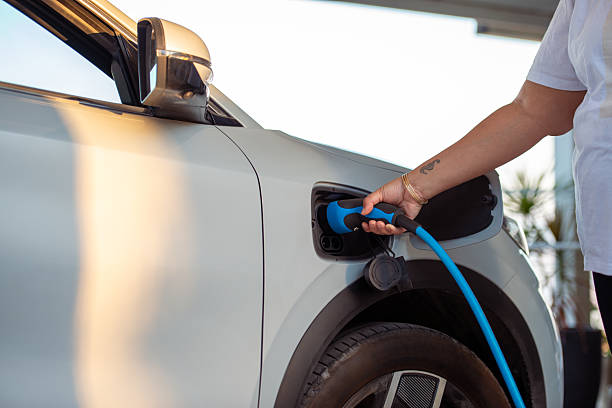 istock Woman Charging Electric Car with Blue Power Cable. 2243377094