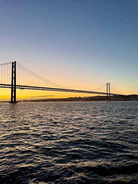 istock Suspension bridge over calm water at sunset 2243378716