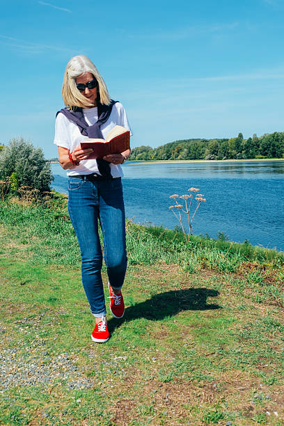 Woman reading by the banks of the Loire River, France.