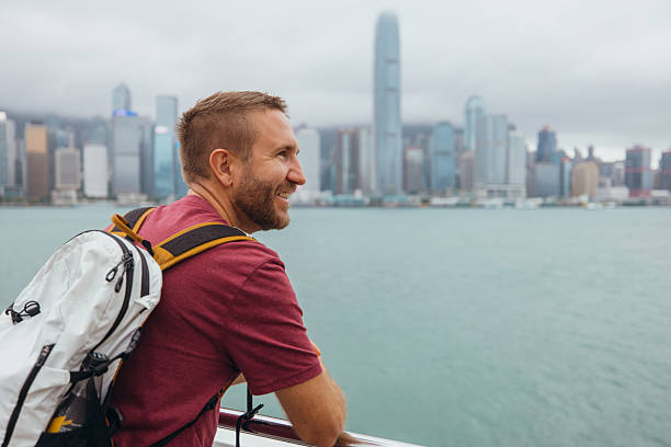 istock Man Enjoying Waterfront City View with Backpack 2243382883