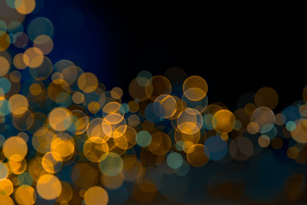Abstract macro photograph featuring soft golden and blue bokeh circles against a deep dark background. The harmonious contrast between warm amber and cool teal tones creates a cinematic and luxurious mood — ideal for backgrounds, Christmas and New Year celebrations, night city lights, luxury branding, and elegant design projects.