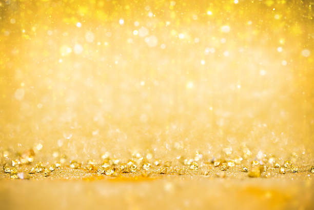 Macro shot of golden glitter and light reflections creating a luxurious, glowing abstract background. The warm yellow tones and sparkling bokeh evoke celebration, joy, and festivity — ideal for Christmas, New Year, or luxury design themes. Perfect for greeting cards, posters, packaging, and high-end advertising with copy space.