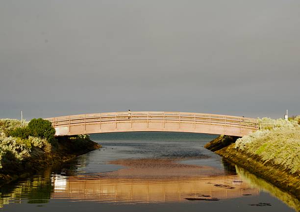 Pedestrian bridge over river mouth on the beach in the morning light