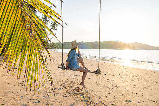 istock Woman Relaxing on Swing at Beach Sunset 2243387995