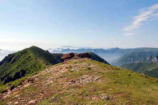 A picturesque mountain peak with green slopes under a clear sky, showcasing natural landscape and outdoor scenery.