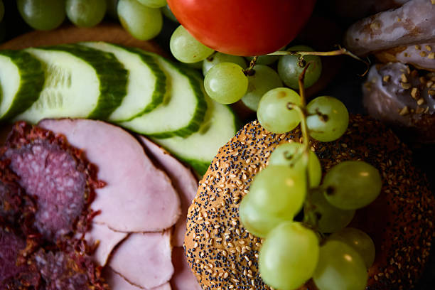 istock Culinary macro with ham salami cucumber grapes cinnamon buns and bagel 2243390385