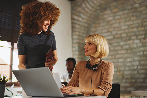 istock Collaborative Office Scene With Two Women Working Together, Laughing, And Sharing Ideas 2243391138