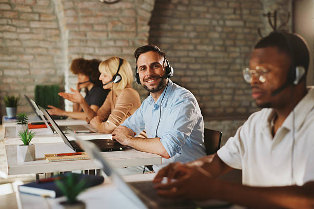 istock Team Call Center Agents Working in Modern Open Office with Headsets and Laptops 2243391599