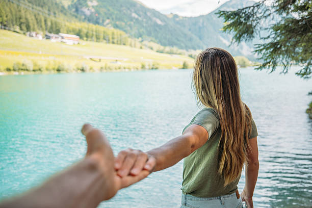 istock Couple holding hands by serene mountain lake at sunset 2243392362