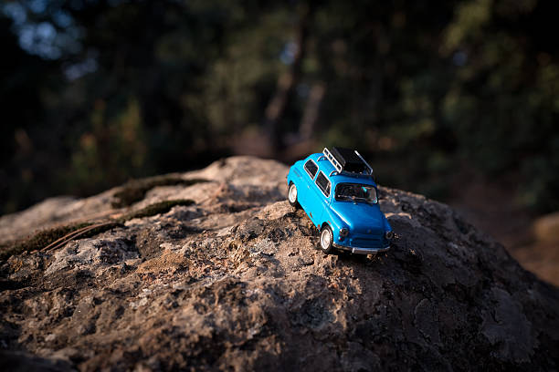 istock Blue toy car on a rock in a lush forest on a sunny day 2243399699
