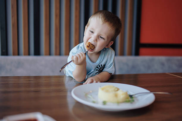 Cute little 2,5 year old boy licking some spilled milk of dining table
