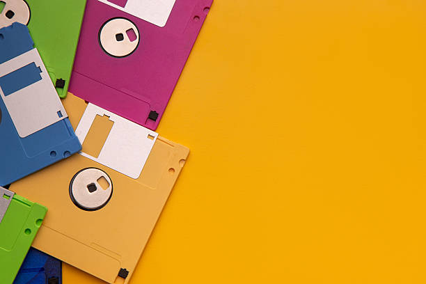 istock Colorful retro floppy disks piled on a bright yellow background. 2243401274