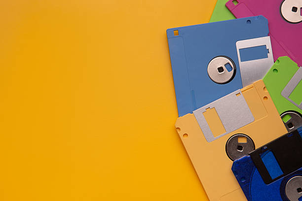 istock Colorful retro floppy disks piled on a bright yellow background. 2243401285
