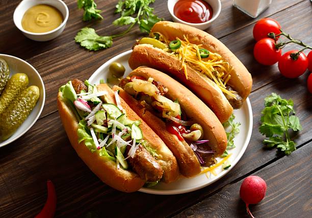 istock Hot dogs loaded with assorted toppings on wooden table 2243402631