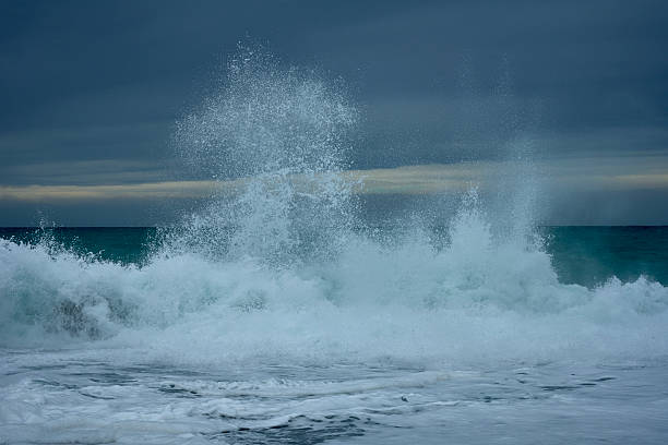 Multiple waves collide and collapse on the shingle shore of Hualien's Pacific coast, filling the frame with whitewater and fine mist under layered clouds. A raw, energetic moment from Taiwan's east coast; no people.
