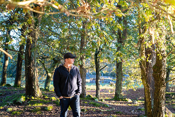 istock Man contemplating while walking in sunny autumn woods 2243404350