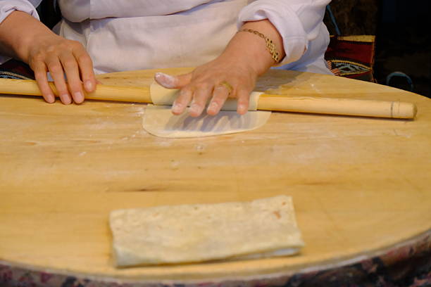 istock Close-up of female hand rolling flatbread dough with rolling pin. 2243404643