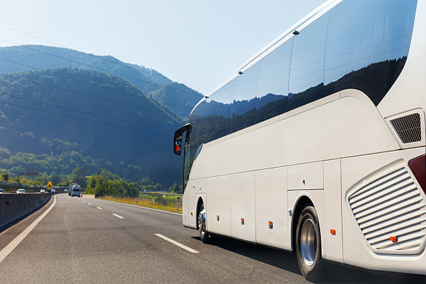 istock Scenic back view big luxury white comfortable tourist bus driving through highway on bright sunny day mountain landscape background. Travel and coach tourism concept. Trip and journey by vehicle 2243405958