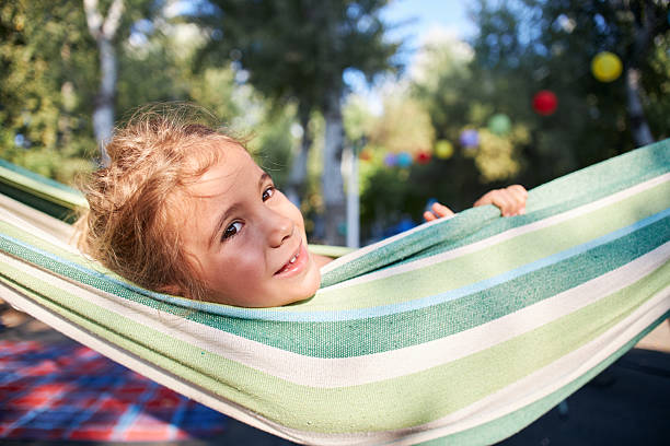 Little girl smiling while enjoying leisure time in a striped hammock outdoors