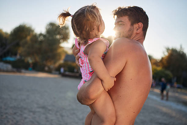 Father and daughter sharing a loving embrace on a beach during sunset