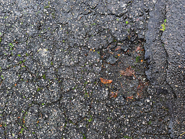 istock Cracks and potholes on damaged asphalt road with rough textured surface 2243408785