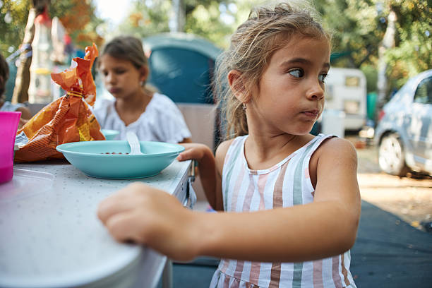 Girl eating breakfast outdoors during summer camping trip