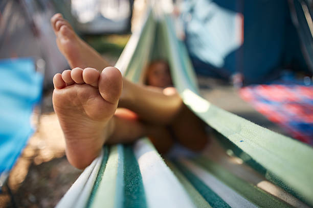 Person's feet are crossed while relaxing in a striped fabric hammock