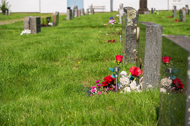istock Graveyard headstone decorated with flowers and angel figurines.. 2243418295