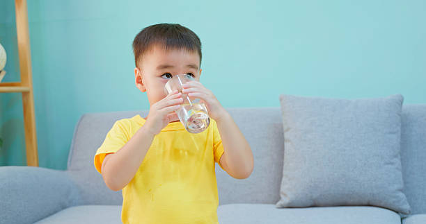 istock Asian boy drinking water in living room 2243422779