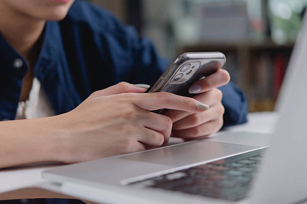 istock Woman hand using smartphone typing, work home office desk laptop. Business technology concept, online communication, social media, multitasking. Remote work, check email, app, browsing internet. 2243426831