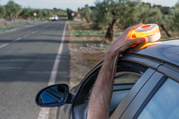 Hand placing V16 emergency warning light on car roof.