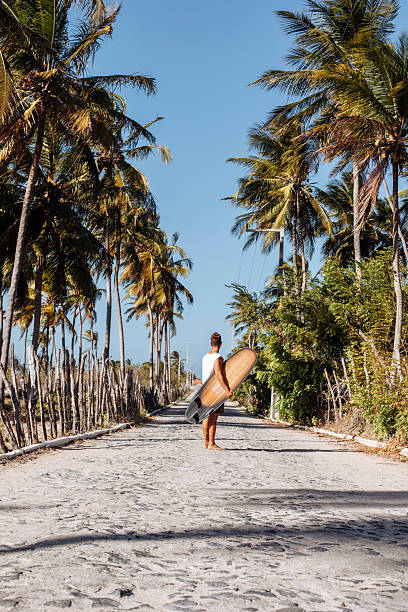 istock young men posing along a tropical road with a surfboard 2243431950