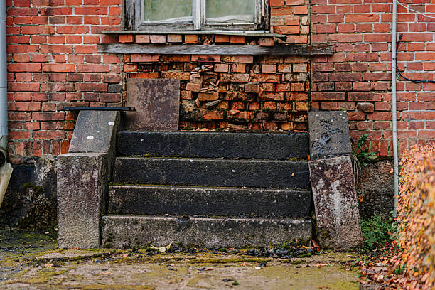 Weathered stone steps ascend to an aged brick wall, highlighting rustic textures and the ambiance of a forgotten urban environment