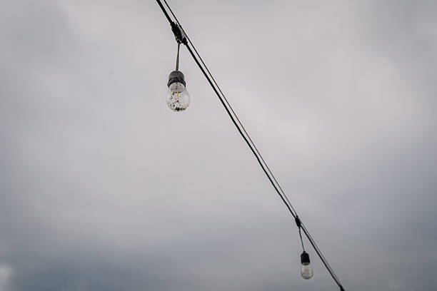Decorative string lights hanging against a moody sky, creating a warm ambiance for outdoor gatherings and enhancing evening atmosphere