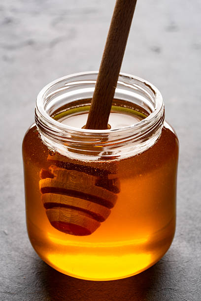 istock Honey jar and honey dipper on black background 2243445834
