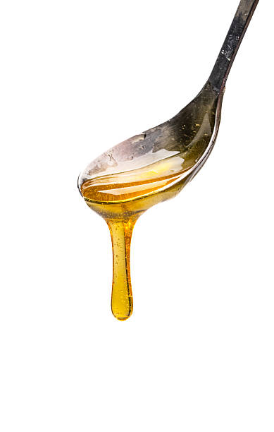 istock Honey dripping from honey spoon on white background 2243445971