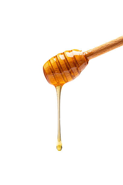 istock Honey dripping from honey dipper on white background 2243446064