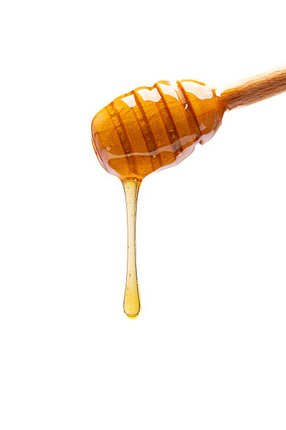 istock Honey dripping from honey dipper on white background 2243446083