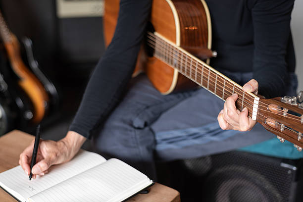 istock Woman writing guitar chords while playing acoustic guitar at home 2243452181