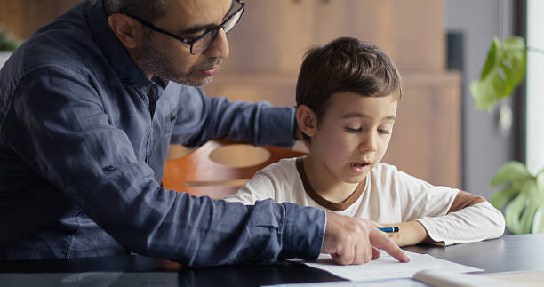 istock Father helping his little son doing his homework 2243452325