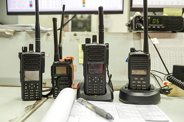 Black walkie talkies stand ready on a desk with documents and a pen, communication tools