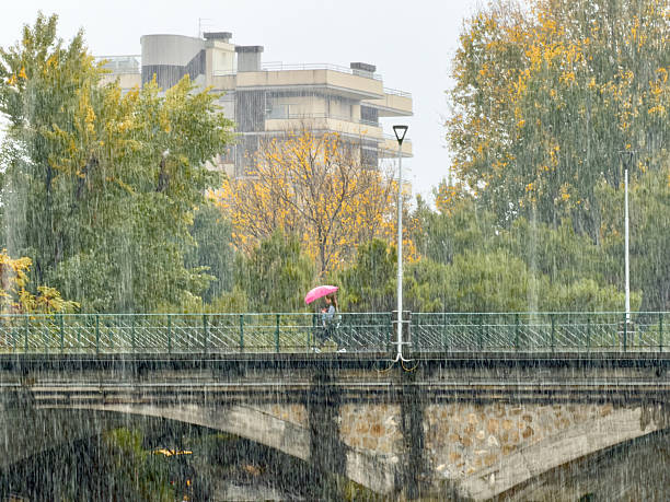 Chiavari, Italy -  October 20,  2025 -A girl with a red umbrella crosses the bridge connecting Ciavari to Lavagna.