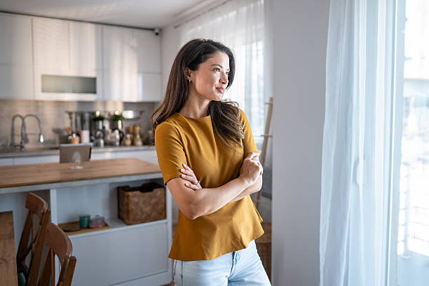 istock Woman with arms crossed confidently looking out window 2243458302