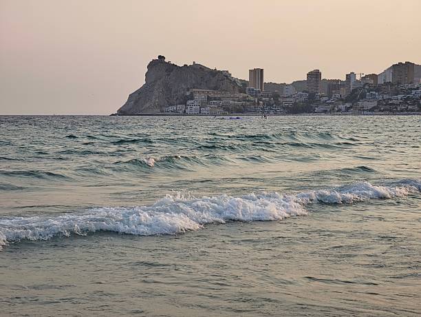 istock Calm ocean with distant village, Tranquil waters beside historic 2243458458